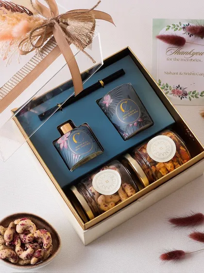 Here is the same hamper of fragrant candles, room fragrance, and gourmet nuts, beautifully packaged with a clear lid and a decorative ribbon, making it ready for gifting.