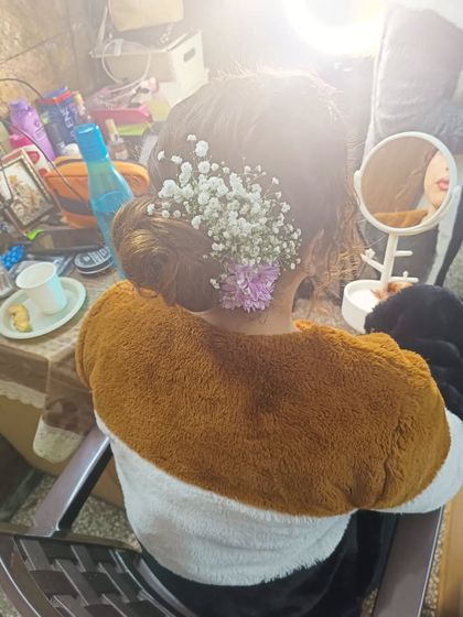 A low bun decorated with baby's breath and a hint of purple flowers. This style is perfect for a bridesmaid or for a bride looking for a subtle floral touch.