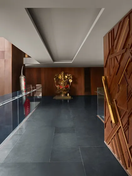 The main door of the Baid Residence, crafted from salvaged wood with a geometric, carved pattern. It stands next to a large Ganesha sculpture, blending rustic materials with spiritual art.