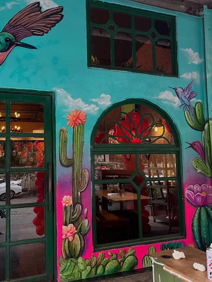 The restaurant facade with its new vibrant mural, showing how the artwork frames the windows and door.