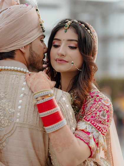 A close-up portrait capturing the bride's intricate jewelry, henna, and the loving embrace of her groom. These details are an essential part of the wedding story.