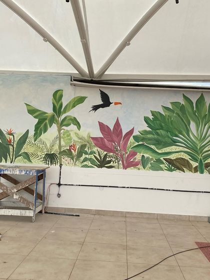 We call this our tropical paradise. We transformed the walls of a restaurant with a misty forest theme, covering even the doors to create a seamless, immersive jungle experience with colorful birds and lush greenery.