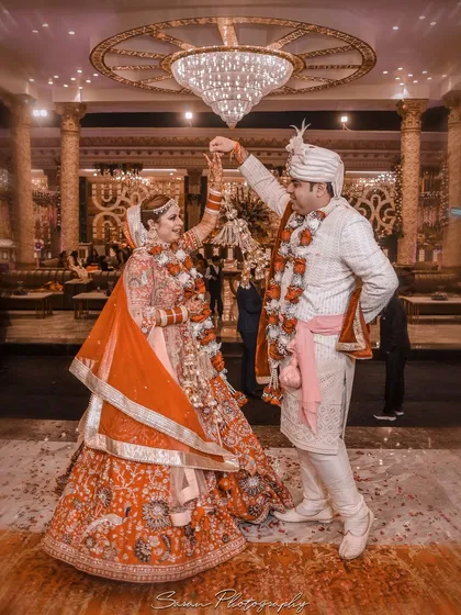 A dynamic shot of the couple dancing under a grand chandelier on their wedding day.