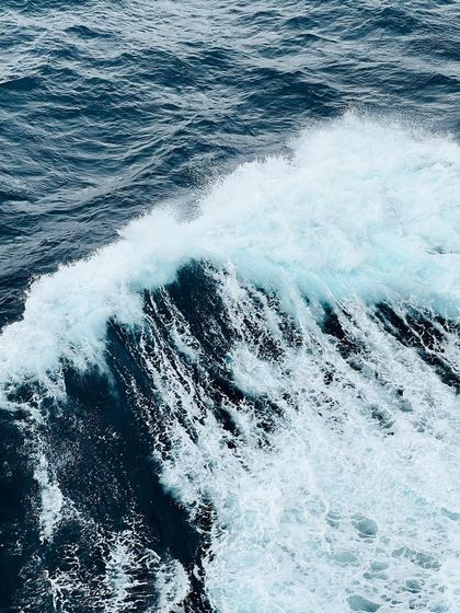 A close-up of a powerful wave breaking in the open ocean, showcasing the raw energy of the sea.