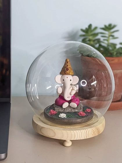 This Ganesha idol, protected under a glass dome, makes a beautiful and serene addition to a work desk, bringing a sense of peace during a busy day.