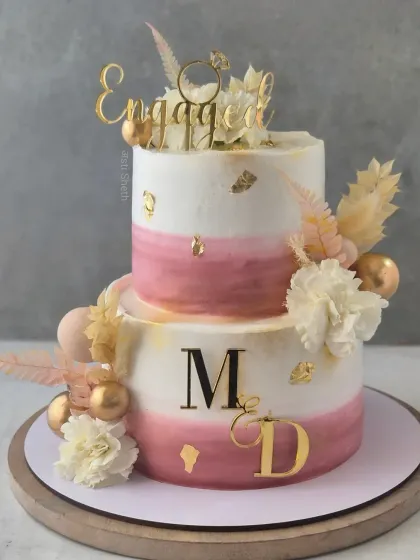 A two-tiered engagement cake in soft wine tones. This 3kg Cherry Chocolate cake is adorned with edible gold leaf and fresh flowers.