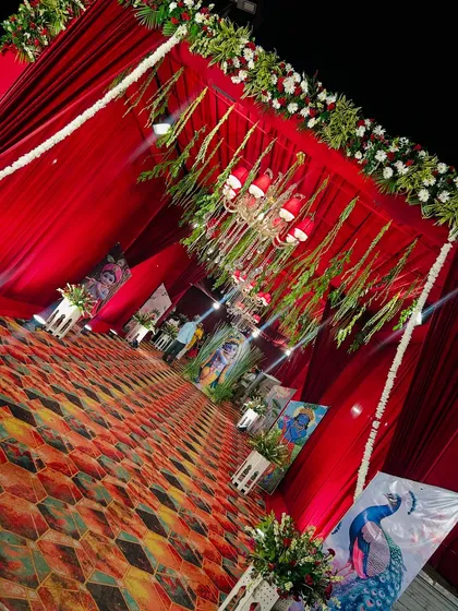 The entrance to the Radha Ashtami celebration was designed to welcome guests into a sacred space. Red drapes, floral borders, and a gallery of religious paintings set a devotional tone right from the start.