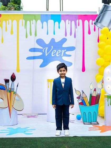 The birthday boy posing proudly in front of his amazing, custom-designed art party backdrop.