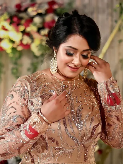 A candid moment of the bride adjusting her jewelry. Her elegant updo and glowing makeup are perfect for a grand reception, ensuring she looks flawless from every angle.