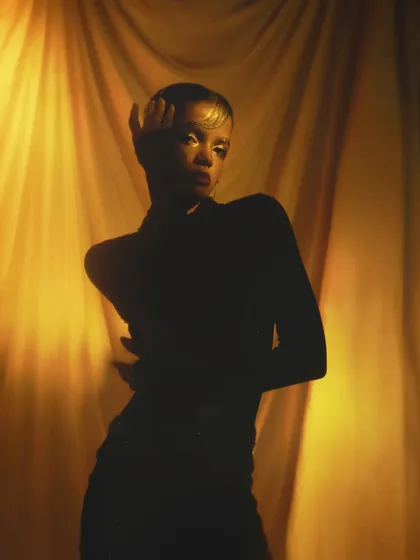 A silhouette shot that uses light and shadow to create a mysterious and artistic mood, with just a hint of the golden makeup visible.