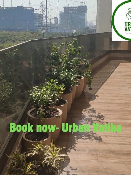 A long balcony lined with potted plants, creating a green border with a beautiful city view.