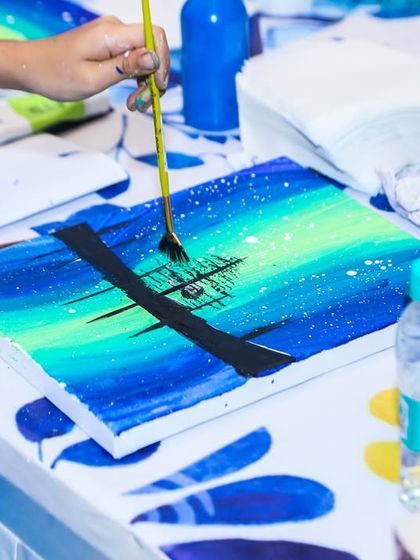 A guest works on their canvas painting, creating a beautiful night-sky scene with guidance from our instructor.