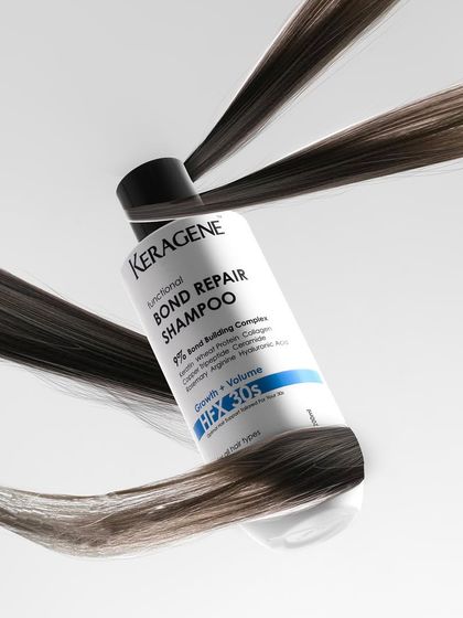 A conceptual shot showing strands of hair wrapping around a bottle of bond repair shampoo, visually communicating the product's function in a creative way.