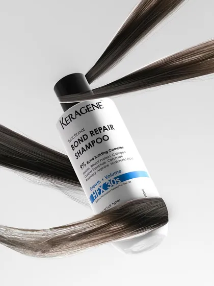 A dynamic and conceptual shot of a bond repair shampoo with strands of hair wrapping around it. This creative visual instantly communicates the product's function in a powerful way.