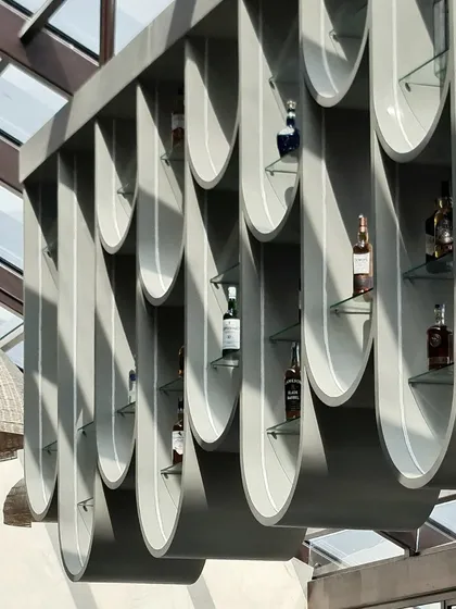 A detail shot of the suspended bar shelving, highlighting its clean lines and the beautiful way it catches the daylight. The design is both highly functional and a significant architectural statement.