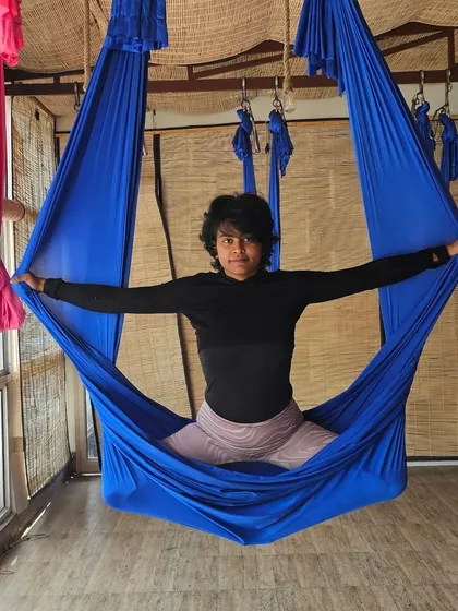 Taking a moment to relax in a seated pose within the aerial hammock. This is a great way to start or end a session, gently stretching the hips and back while feeling secure in the silk.