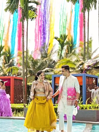 A wider view of the couple's entrance, showcasing the rainbow smoke trails and the poolside setup. Every detail was curated to fit the vibrant, carefree Coachella theme.