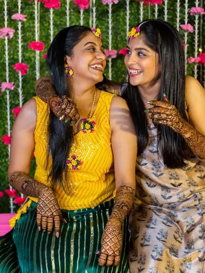 Two friends sharing a happy, candid moment together at the mehendi ceremony.
