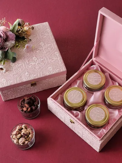 Our Chikankari Box in pink is a perfect blend of tradition and taste. It's filled with four jars of treats like rose cashews, brownie bites, and honey choco almonds.