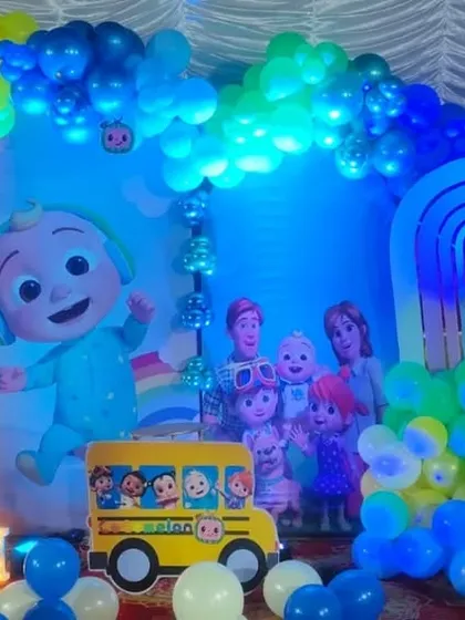 A Cocomelon-themed first birthday stage with a blue and rainbow color scheme.