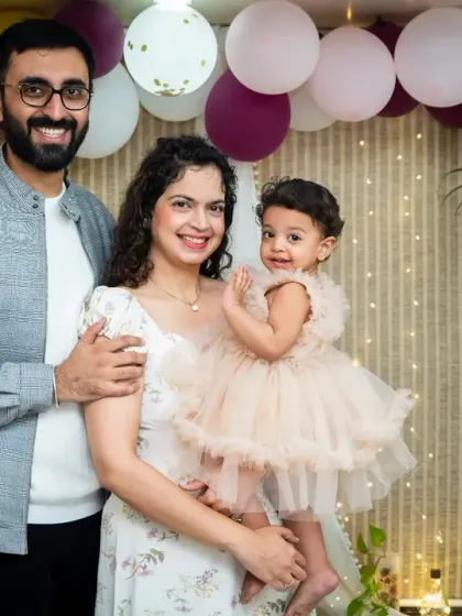 A lovely family portrait taken during a first birthday photoshoot, with the parents and their daughter posing together.