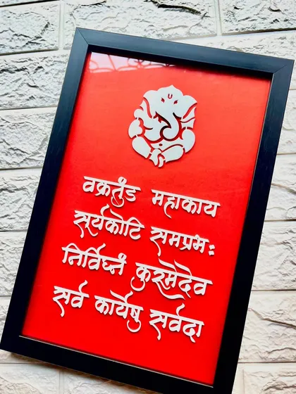 A stunning 'Vakratunda Mahakaya' wall frame. The bold red background makes the white lettering and Ganesh silhouette pop, creating a powerful visual statement.