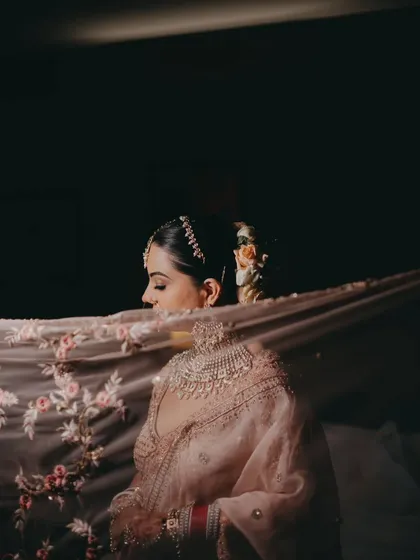 A moody and romantic bridal portrait, with the bride's face partially obscured by her delicately embroidered dupatta.