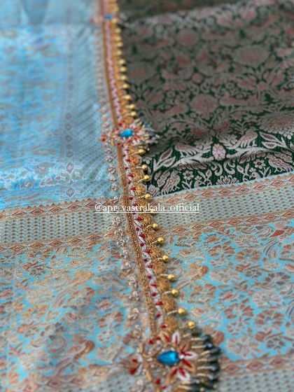 A rich border with blue and red stone work, separating a light blue brocade from a dark green one.