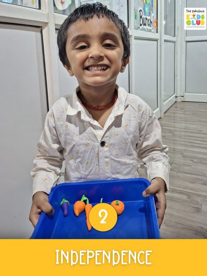 Look at that proud smile! This little one is showing off the clay vegetables he made. This activity not only builds fine motor skills but also fosters a sense of independence and accomplishment.