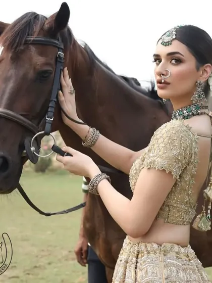 A model in bridal wear adjusts the horse's bridle, an elegant and interactive shot.
