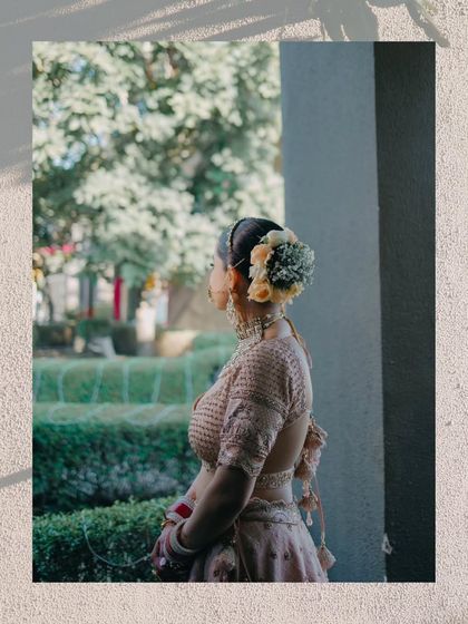 A shot from behind, focusing on the bride's elegant hairstyle adorned with flowers, as she looks out a window.