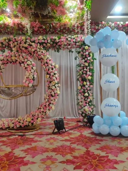 A closer look at the naming ceremony stage, featuring a floral cradle frame and a unique balloon arrangement with custom names printed on them.