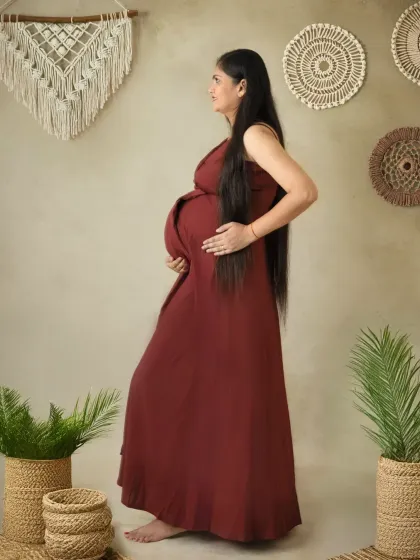 A beautiful profile shot in a boho-themed setting. The earthy tones of the dress and decor create a warm, natural, and grounded maternity portrait.