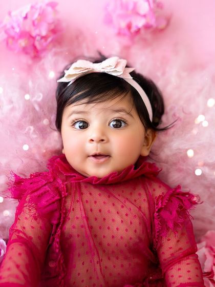 A close-up of this beautiful six-month-old baby girl, with her big, curious eyes, in a stunning pink butterfly-themed setup.