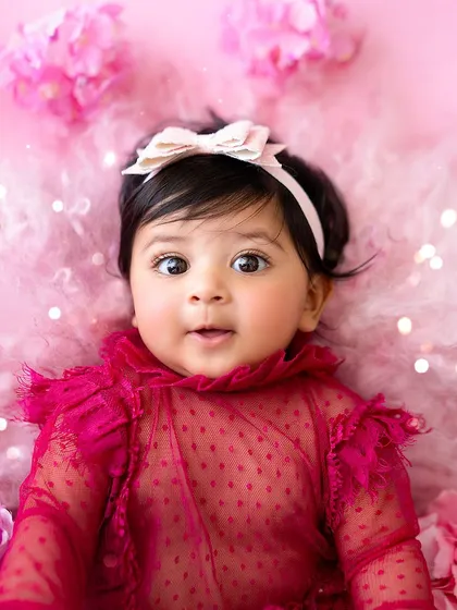 A close-up of this beautiful six-month-old baby girl, with her big, curious eyes, in a stunning pink butterfly-themed setup.