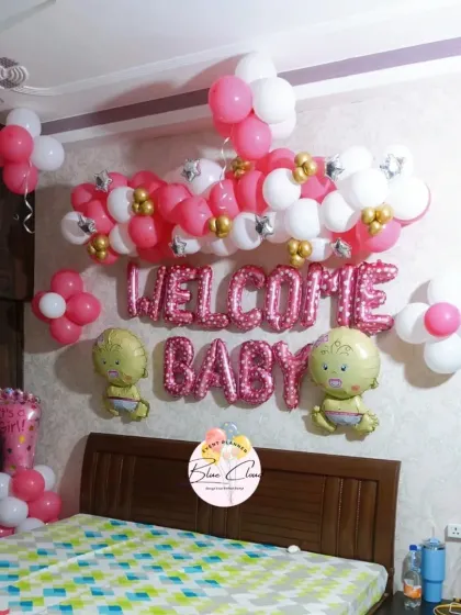 A lovely bedroom decoration to welcome a baby girl, with a pink and white balloon garland and 'WELCOME BABY' foil letters.