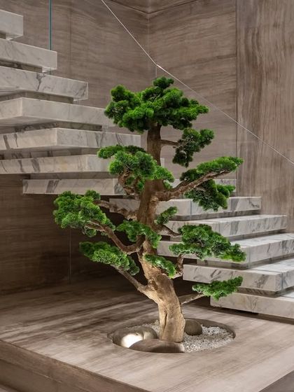 An artificial bonsai tree is perfectly positioned to complement the strong lines of a floating marble staircase. This view shows how the tree's organic form softens the modern architecture.