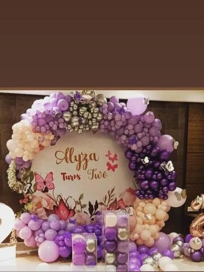 A gorgeous butterfly-themed second birthday for "Alyza", featuring a custom backdrop and a lush balloon ring in shades of purple and pink.