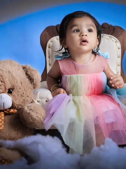Looking up in wonder, this little girl is captivated by the studio environment. This candid shot highlights the beauty of the rainbow theme and the child's innocence.