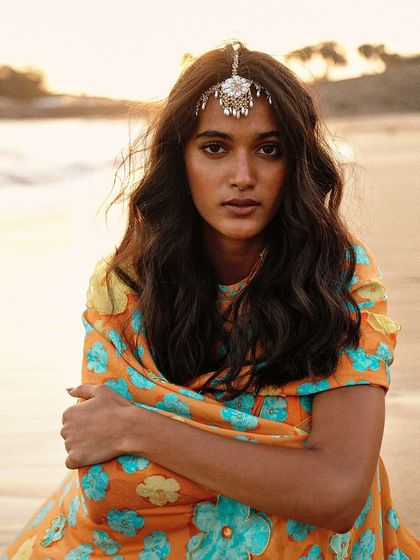 A beautiful beach shot of a model wearing our bestselling pearl teeka, showing its versatility.