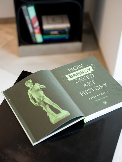An open copy of 'How Banksy Saved Art History.' We believe in providing context and deeper knowledge alongside the art we showcase.