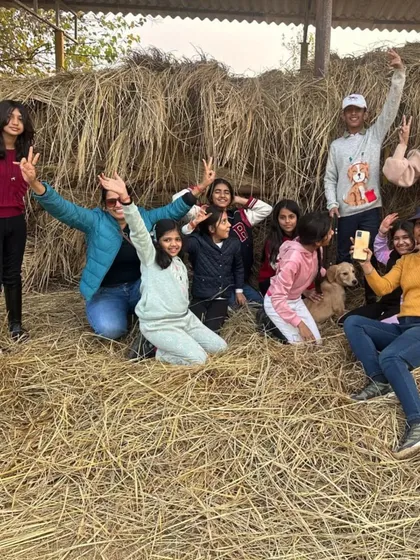 A happy group poses for a photo on a haystack during a Christmas party, capturing the rustic holiday spirit.