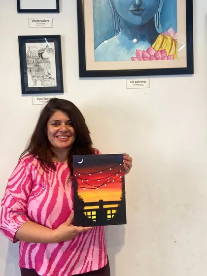 A participant with her finished sunset canvas painting. The warm colors and silhouette create a beautiful and evocative scene.