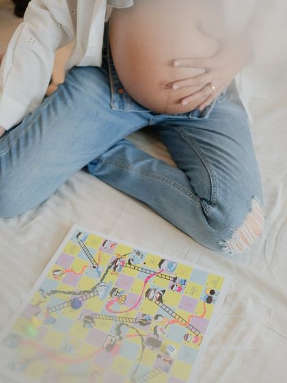 Incorporating fun props like a board game can add a unique and personal touch to your maternity photoshoot, representing the fun times to come.