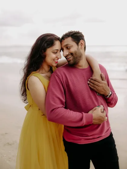 An intimate pre-wedding portrait of a couple on a beach, their smiles reflecting the joy of their relationship.