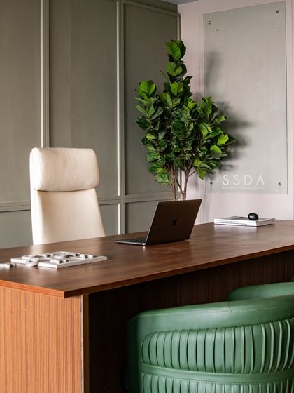 The desk area in our studio, featuring a clean, modern aesthetic with warm wood, a comfortable leather chair, and a touch of green from a fiddle-leaf fig.