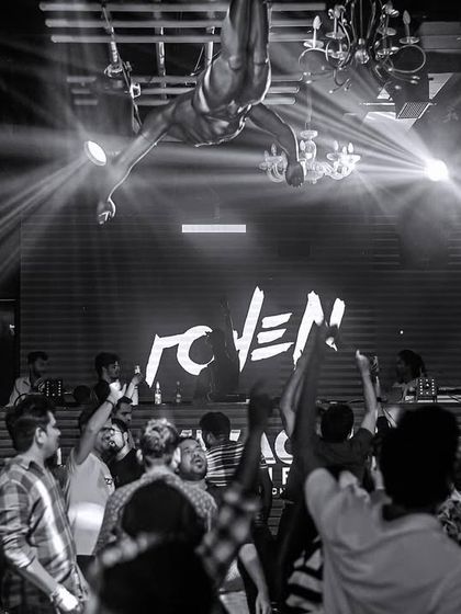 A black and white shot of the unique setup at Mikachi Club in Pune, featuring an acrobat above the DJ booth.
