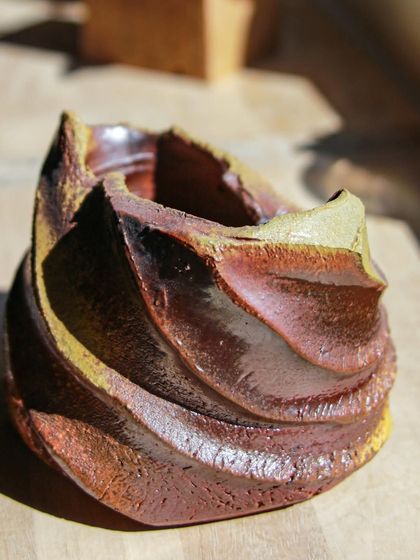 This wood-fired vessel, with its swirling texture and rich brown and yellow hues, is a testament to the transformative power of the kiln. It’s a piece of functional sculpture, perfect for holding a single stem.