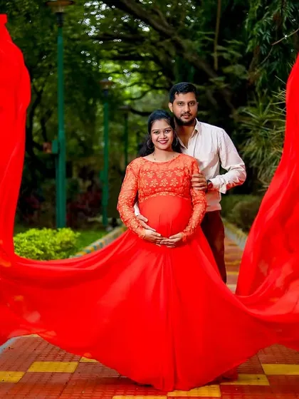 A breathtaking outdoor portrait capturing the joy of expecting parents. We love using dramatic, flowing gowns like this vibrant red one to create stunning, memorable images in Bangalore's beautiful parks.