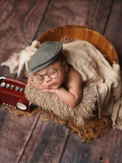 A wider shot of the vintage-themed setup, showing the newborn sleeping in a wooden bucket. The rustic props and textures work together beautifully.